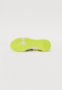Semelle de chaussure en caoutchouc jaune vif avec un motif texturé, présentant des rainures et des formes ovales pour l'adhérence ; accent blanc le long du bord.
