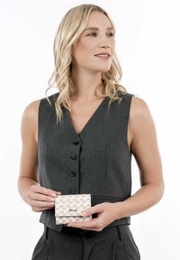 Gray sleeveless top with buttons; model holds a light beige wallet featuring a geometric pattern and a logo on the front.