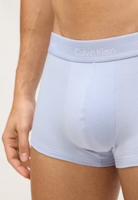 Boxeri de culoare albastru deschis confecționați dintr-un material moale de bumbac. Prezintă un brâu elastic cu logo și o croială strânsă, cu cusături netede.
