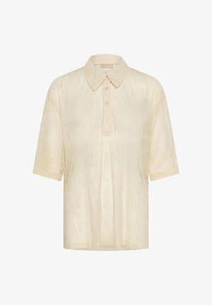 Beež lühikeste varrukate ja pitsilise kraega bluus, kus on kolmesuunaline nööpide rivi ning õrn lilleline pitsimuster.