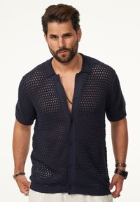 Marineblaues, gestricktes Kurzarmhemd mit Netzmuster, Knopfleiste und flachem Kragen. bietet eine lockere Passform sowie gerippte Bündchen und Saum.