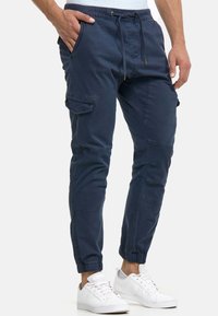 Marinblå cargobyxor i lätt tyg med avsmalnande ben, elastiska muddar, sidfickor och dragsko i midjan med gulddetaljer.