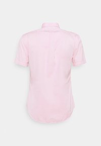 Chemise à manches courtes de couleur rose clair, dotée d'un col standard, d'une texture lisse et d'un ourlet arrondi avec un détail de couture au dos.