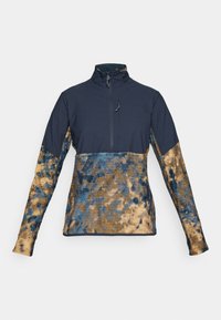 Dvigubo užtrauktuko fleece megztinis su tamsiai mėlynu viršutiniu kūnu ir apykakle, o rankovėse ir apatinėje torso dalyje yra mėlino ir rudai margintų raštų.