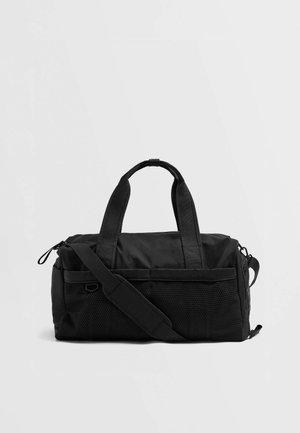 Sac de sport noir avec des poches avant en maille, deux poignées supérieures, une bandoulière et des compartiments zippés, sur un fond uni.