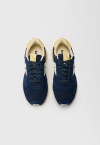 Sneakers blu navy realizzati in materiali mesh e suede, con un design a lacci, accenti crema e suola in gomma con una finitura testurizzata.