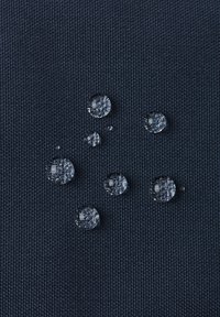 Wassertropfen auf einem dunkelblauen strukturierten Stoff, die unterschiedliche Größen und Klarheit zeigen und die wasserabweisenden Eigenschaften hervorheben.