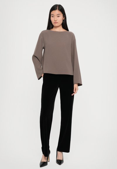 Haut marron à manches longues avec un décolleté bateau associé à un pantalon en velours noir à jambes larges et des chaussures à talons hauts noires. Design simple et texture lisse.