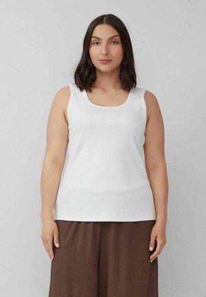 Weißes Tanktop, ärmellos, Rundhalsausschnitt, gerippte Textur, schlichtes Design. Kombiniert mit lockeren, braunen, strukturierten Hosen.