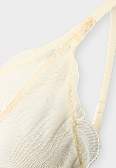 Bonnet de soutien-gorge en dentelle crème délicate avec bords festonnés et broderie en spirale, doté d'une bretelle réglable et d'un tissu en maille fine.