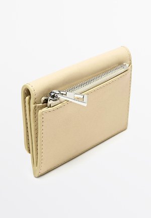 Beżowy portfel ze skóry z przedziałkiem na suwak, o gładkiej teksturze, prostokątnym kształcie i detalem w postaci kontrastującego przeszycia.
