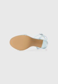 Sandal de tacón alto azul claro con tiras, parte superior lisa, puntera redondeada y suela texturizada de color marrón claro. Presenta una hebilla metálica.