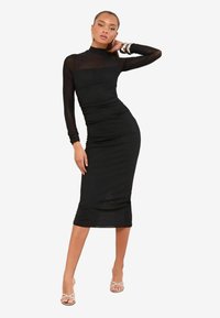 Rochie neagră tip bodycon cu mâneci lungi din material transparent și decolteu înalt. Prezintă detalii plisate, hem lungime până la genunchi și o textură netedă. Bijuterii de accent.