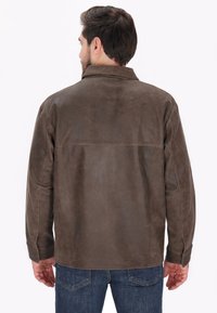 Veste en cuir marron avec une texture lisse, dotée d'un col et de manches longues. Le design comprend une coupe droite et des détails de couture discrets.