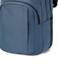 Blauwe stoffen rugzak met een gestructureerde afwerking, voorzien van meerdere zakken en zwarte ritsaccenten, ontworpen voor duurzaamheid en functionaliteit.