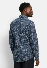 Navyblaues Langarmhemd mit einem weißen Paisleymuster. Mit Kragen und Knopfmanschetten, aus glattem, leichtem Stoff gefertigt.