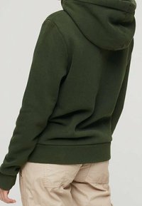 Olivgrön hoodie med mjuk textur, med en stor huva och ribbad mudd samt nederkant. Designad med en avslappnad passform.
