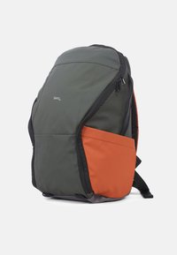 Rugzak met een grijsgroene hoofdmateriaal en een oranje zijvak. Gladde textuur, strak ontwerp, met ritsen en verstelbare banden.