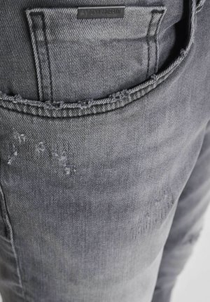 Grijze denim jeans met een versleten ontwerp, franje aan de zakranden en een reliëf merklabel op de achterzak.