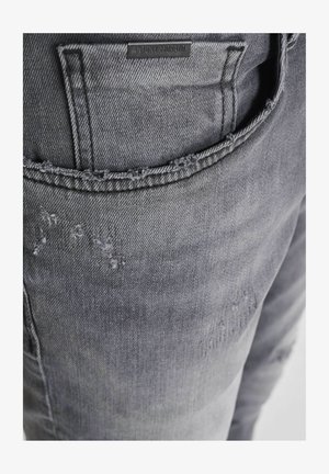 Grijze denim jeans met een versleten ontwerp, franje aan de zakranden en een reliëf merklabel op de achterzak.