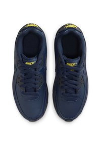 Nike tossud tumesinises nahast kollaste aktsentidega, ümarate varvastega, paeltema disainiga ja pehmendatud kaelusega mugavuse tagamiseks.