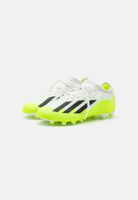 Botas de fútbol verde lima con rayas negras, cordones blancos y una parte superior texturizada. Diseñadas para ofrecer agarre con una suela moldeada y tacos.