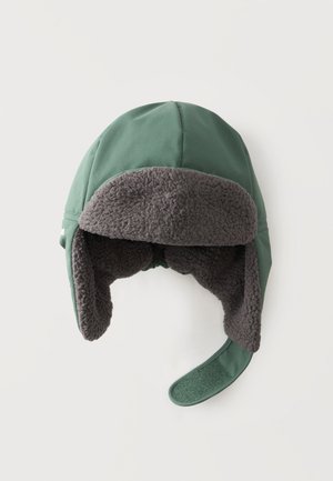 Gorro trampa de invierno verde con forro de felpa gris oscuro y orejeras, una solapa extendida con cierre de velcro verde visible.