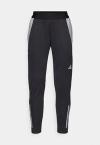 Black athletic pants with a fitted design, featuring light gray side panels and subtle three-stripe accents near the ankles.