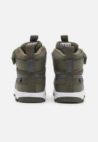 Olivgröna högsko-sneakers med vadderad krage, texturerat bakstödsskena och vit gummisula. Har en dragflik för enkel användning.