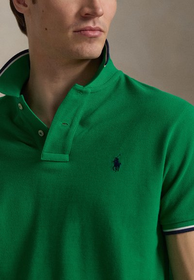 Φωτεινό πράσινο πόλο με υφασμάτινη υφή, πατιλέτα με τρία κουμπιά και ριμπ κολάρο με μπλε σκούρες λεπτομέρειες. Κεντημένο λογότυπο στο στήθος.