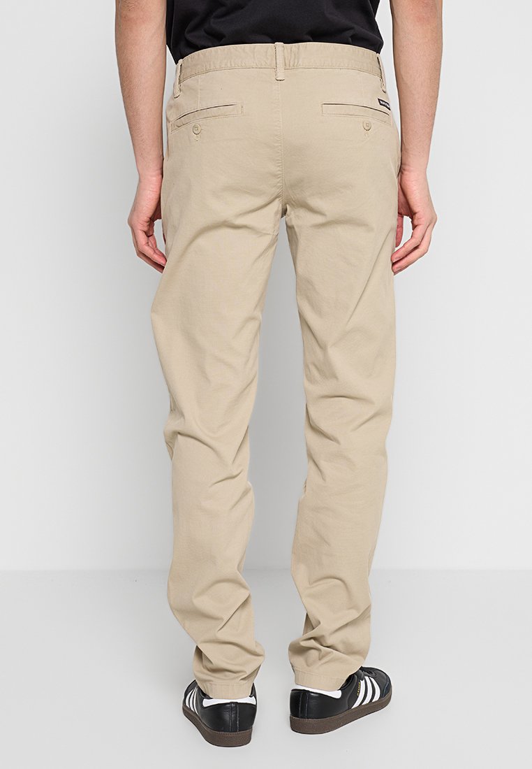 Beżowe bawełniane spodnie o prostym kroju, z dwiema tylnymi kieszeniami, paskiem z szlufkami oraz subtelnymi detalami w szwie.