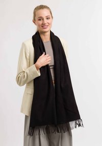 Must mustriba pehmeast materjalist, frippidega, kantud heledat värvi pluusi kohal koorevärvi bleiseri all. Lihtne ja elegantne disain.