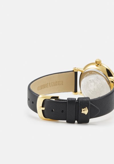 Black genuine leather watch strap with gold-tone hardware, featuring a lion head detail. The back is engraved with "Genuine Leather."