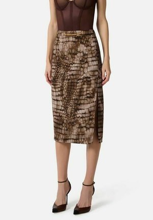 Donna che indossa una gonna marrone fantasia al ginocchio con spacco laterale, top marrone trasparente e scarpe marroni con tacco alto e cinturino alla caviglia.