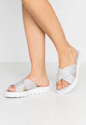 Grå slidesandaler i imiteret krokodilleskind med tyk hvid platformsål, med krydsede stropper og åben tå. Glat tekstur.