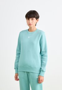 Lichtblauwe sweatshirt gemaakt van zachte stof met een ronde hals en ribbelmanchetten, met een klein wit Nike-logo op de borst.
