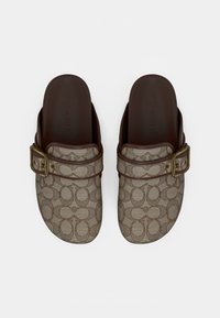 Brune slip-on-træsko med mønster, der har et signaturdesign, justerbar spænde og gummisål. Tekstureret stof med en glat finish.