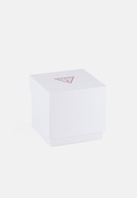 Biały kwadratowy pudełko o teksturowanej powierzchni, z czerwonym trójkątnym logo na górze. Zaprojektowane do pakowania, z gładkim dnem i krawędziami.