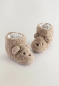 Braune Plüschhausschuhe mit flauschiger Außenseite und weißem Innenfutter. Mit einem tierähnlichen Gesicht, 3D-Ohren und kleinen Nasendetails. Weiche Textur.