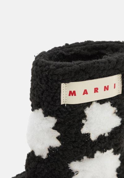 Bota difusa en blanco y negro con un patrón de estrellas, tela suave al tacto, y una etiqueta beige con letras rojas que dice "MARNI".