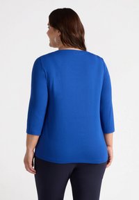 Niebieski, elastyczny top z trzema ćwierć rękawami i szerokim dekoltem, o gładkiej fakturze i prostym designie. Brak widocznych wzorów czy akcentów.