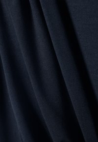 Dunkel marineblauer Stoff mit einer glatten, leicht strukturierten Oberfläche, der Falten und Drapierungen zeigt, die auf ein leichtes, weiches Material hinweisen.