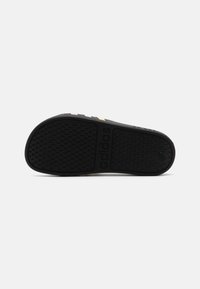 Schwarzer Sneaker-Außensohle mit strukturiertem Grip, ausgestattet mit mehrfarbigen Streifen (lila, gelb und grün) und geprägtem "adidas"-Branding.