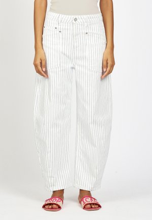 Weiße High-Waist-Hose mit weitem Bein und dünnen vertikalen schwarzen Streifen, kombiniert mit pinken, offenen Zehenpantoffeln mit Textdetails.