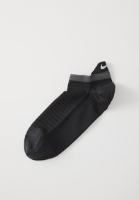 Čierna športová ponožka s textúrovanou podrážkou, tonálnym pruhovaním, ribovaným členkom a čiernym logom Nike na vrchu. Vyrobená z elastického materiálu.
