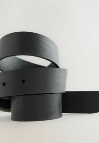Cinturones de cuero negro dispuestos en una pila suelta, con una superficie texturada, bordes limpios y formas cilíndricas con agujeros para ajuste.