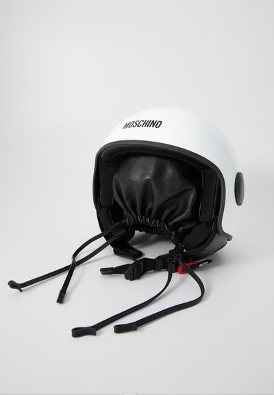 Hvid Moschino hjelm med en sort inderfoering. Har justerbare stropper og en tætsiddende pasform omkring bunden. Bemærkelsesværdigt logo på fronten.