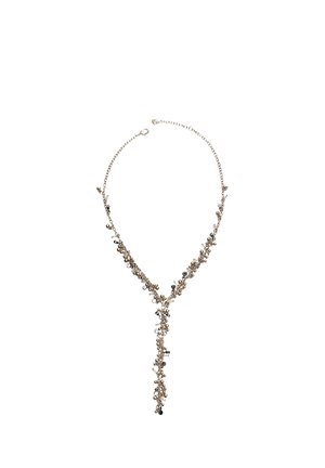 Collier délicat en chaîne d'or avec de petites perles noires et transparentes formant un pendentif en forme de goutte en Y sur fond blanc.
