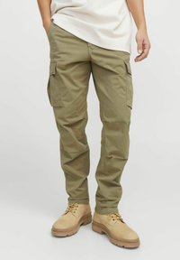 Khaki Cargo-Hosen aus einem Baumwollmix mit mehreren Seitentaschen, taillierter Passform und weichem, strukturiertem Stoff, kombiniert mit beigen Stiefeln.