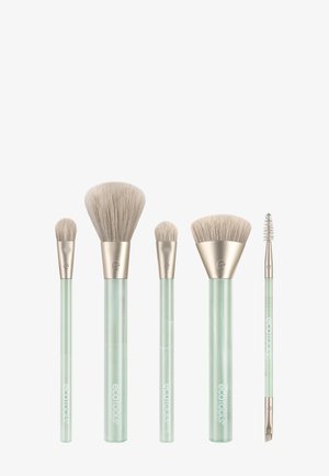 Cinco brochas de maquillaje con mango verde y cerdas claras, dispuestas en fila sobre un fondo blanco.